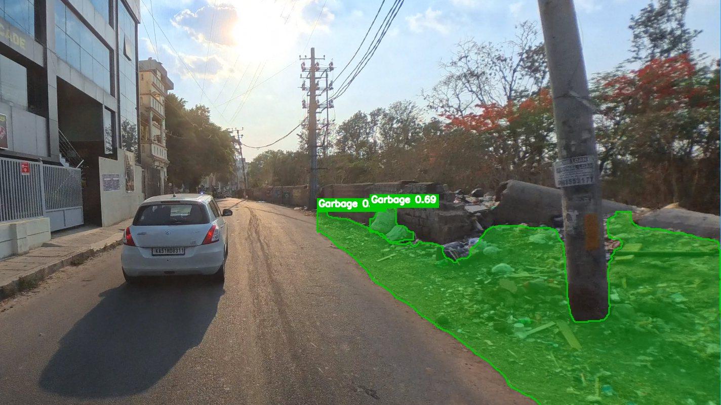 A garbage pile along a roadside wall, outlined in green by the detection model