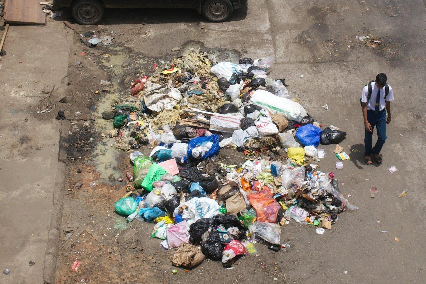 The same street a little further along: a large spread of dumped garbage beside the parked cars