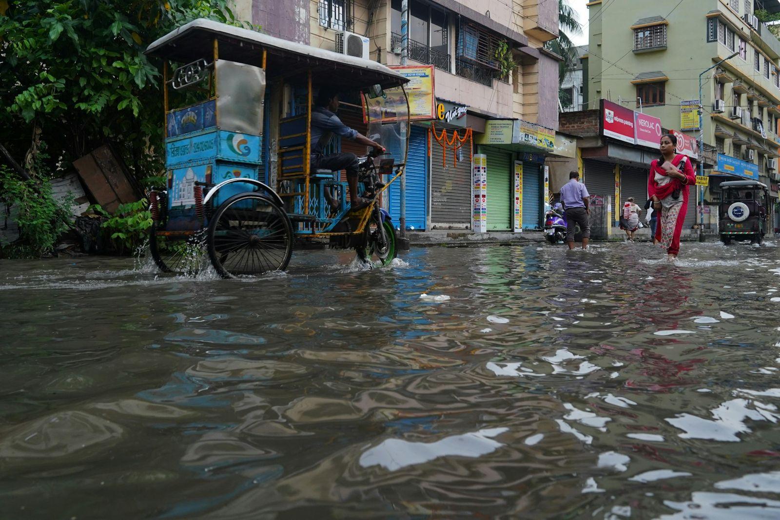 A flooded street in Kolkata during the monsoon, a cycle rickshaw wading through